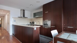 Una cocina moderna con armarios de madera oscura, electrodomésticos de acero inoxidable y una mesa de comedor con superficie de vidrio.