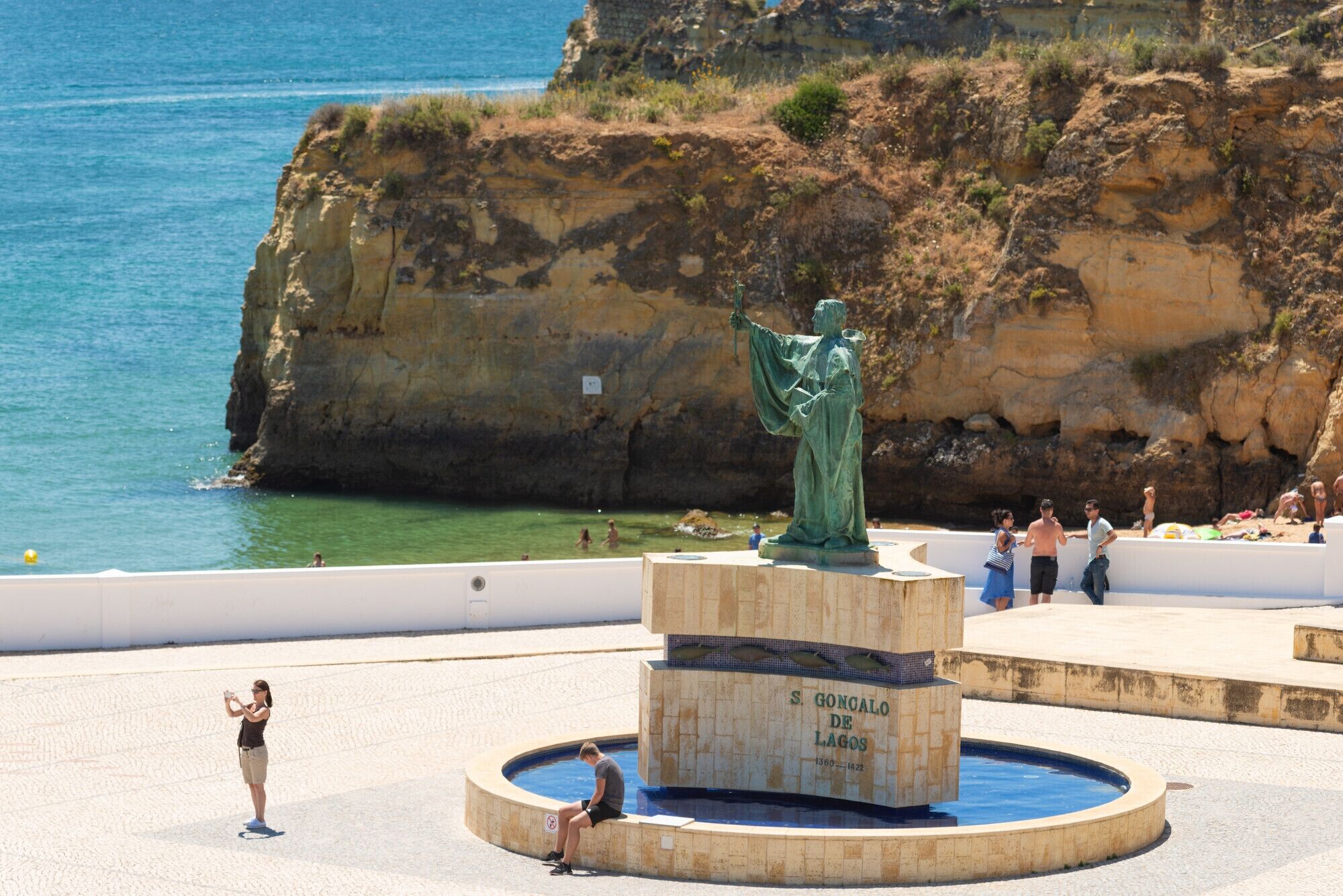 A statue of a figure holding a staff, surrounded by a circular pool with a sign reading "S. Goncalo de Lagos".