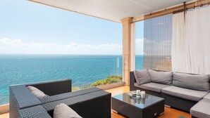 A balcony with a view of the sea, furnished with a sofa and a coffee table.
