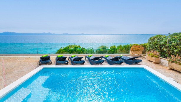 A swimming pool with lounge chairs and a view of the sea.