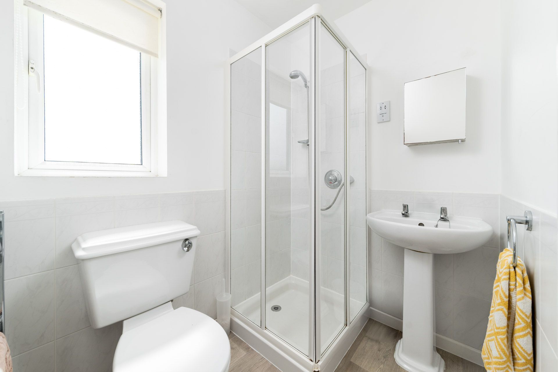 Ein modernes Badezimmer mit Toilette, einer begehbaren Glasdusche und einem Waschbecken auf Säule.