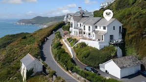 Una casa costera con entrada pavimentada, un garaje separado y un balcón con vistas al mar.