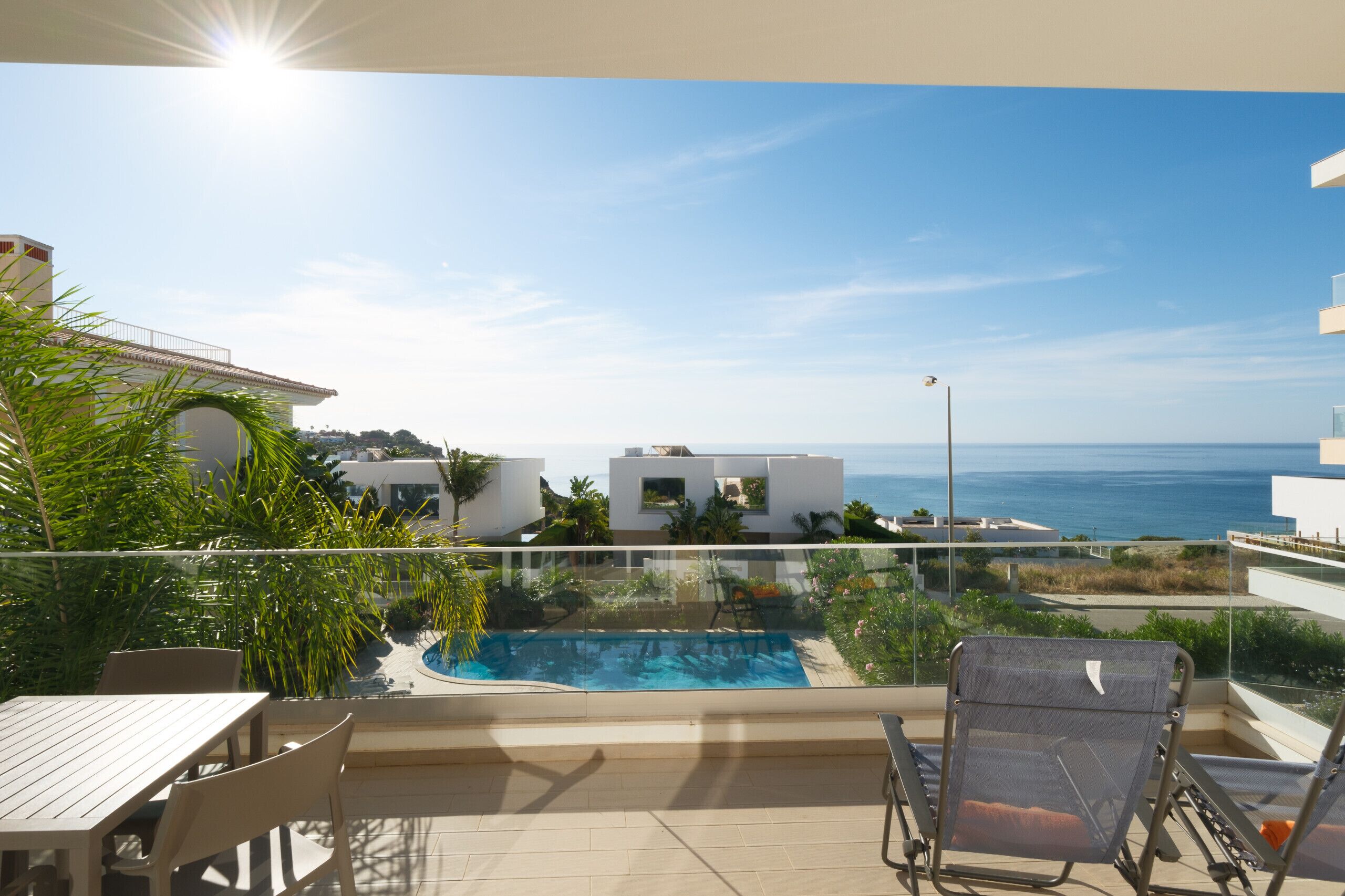 Un balcon avec une piscine, des chaises et une vue sur la mer.