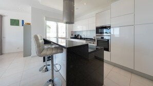 Een moderne keuken met witte kasten, een zwart aanrecht en roestvrijstalen apparatuur.