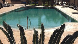 A swimming pool with lounge chairs and palm trees.