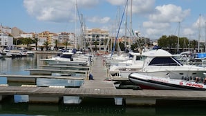 A marina with multiple boats docked along a wooden pier.