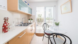 A modern kitchen with a white countertop, wooden cabinets, and a dining area with a table and chairs. - CAN GARRETA - Beautiful holiday home near the beach. Free WiFi (Alcúdia)
