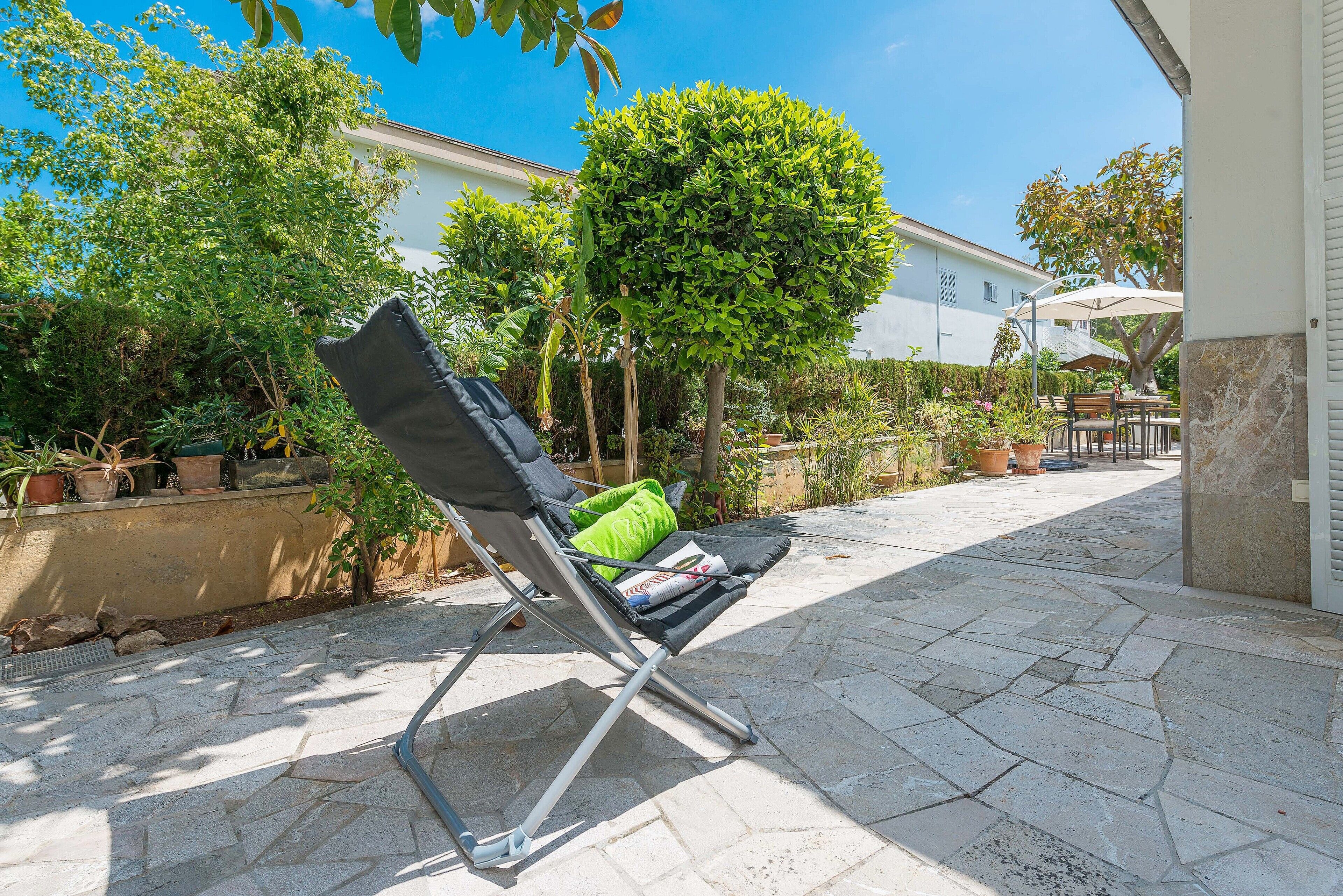 A patio area with a folding chair, a table, and potted plants.
