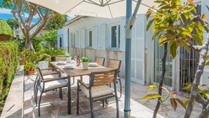 An outdoor patio with a table and chairs, a large umbrella, and potted plants. - CAN GARRETA - Beautiful holiday home near the beach. Free WiFi (Alcúdia)