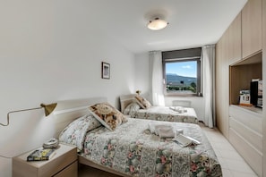 Camera da letto con due letti, un comodino, una scrivania, una lampada, una finestra con vista e un lampadario.