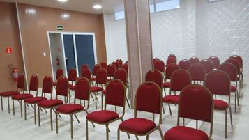 A conference room with rows of red chairs and a white tiled floor.