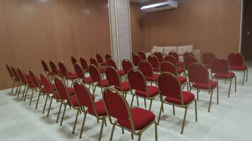 A conference room with rows of red chairs and a white ceiling.