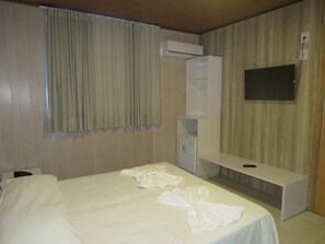 Habitación de hotel con cama, escritorio, televisión de pantalla plana y aire acondicionado.