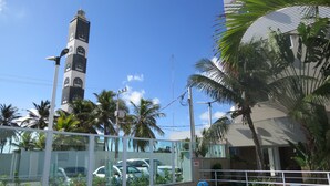 Una piscina con borde de azulejos, un edificio alto con una torre de reloj y palmeras.