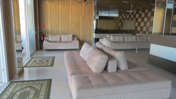 A modern living room with a large beige sofa, a smaller sofa, and a patterned rug.