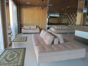 Un salon moderne avec un grand canapé beige, un canapé plus petit et un tapis à motifs.