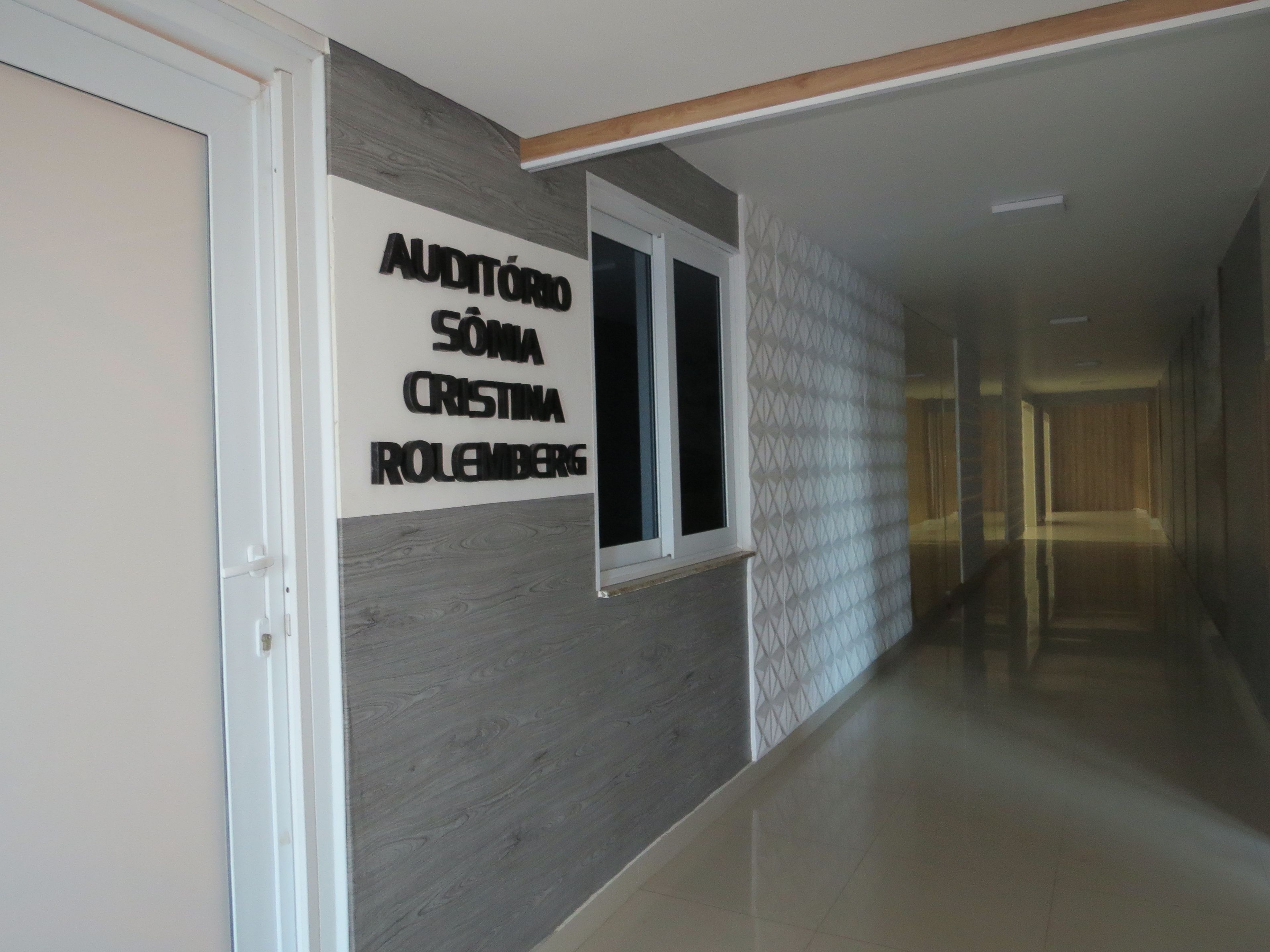 Un pasillo con un cartel que dice 'AUDITÓRIO SÓNIA CRISTINA IROLEMBERG' en la pared.