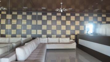 A modern lobby with a sectional sofa, a reception desk, and a patterned wall.