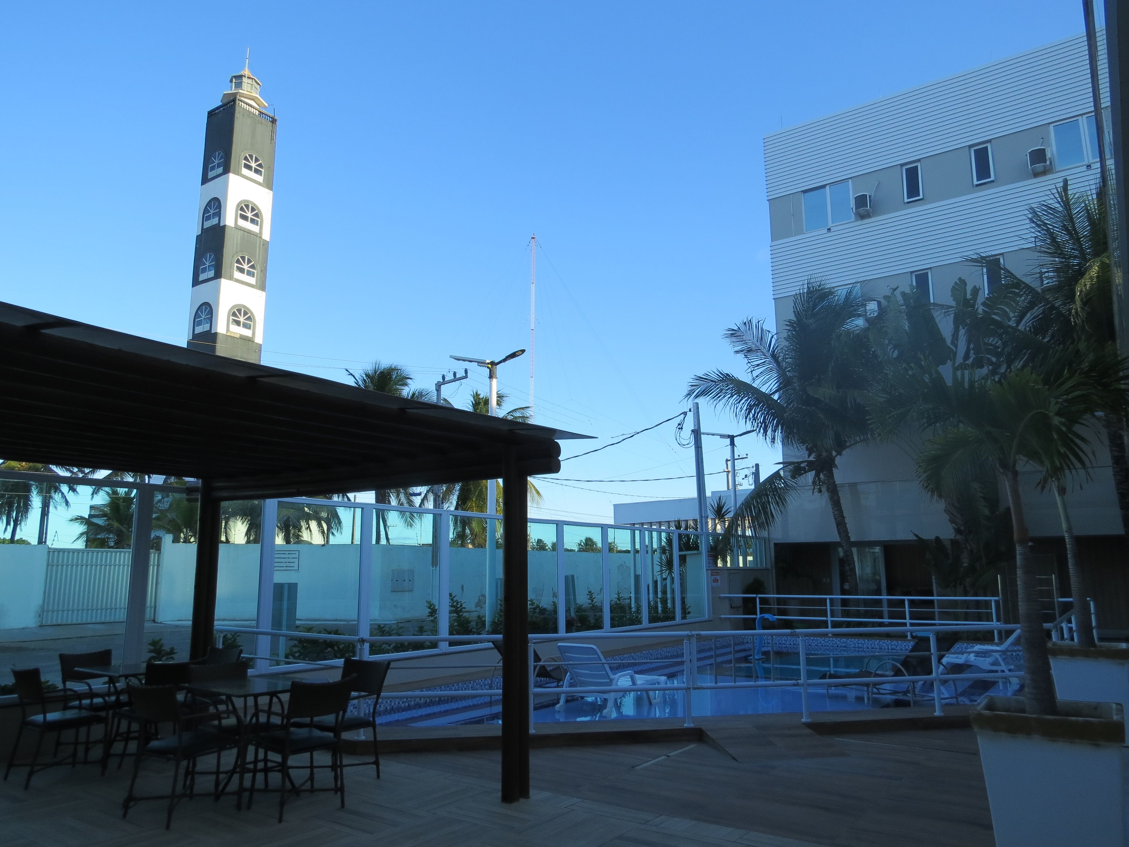 Un área de estar al aire libre con mesas y sillas, una piscina y vistas a un edificio alto con una torre de reloj.