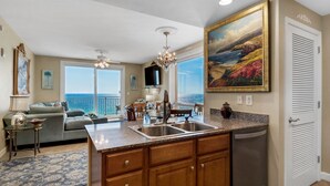 Una cocina con una isla grande, un comedor con vistas y una sala de estar con sofá y mesa de centro.