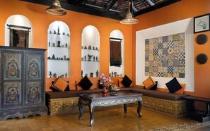 Una habitación con sofá, una mesa, estanterías decorativas y un papel tapiz estampado.