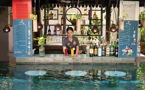A bar area with a drink menu, various bottles, and a pool with floating objects. - Boutique Indochine Hotel - SPA (Siem Reap)