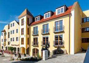 Ein gelbes Gebäude mit mehreren Balkonen und einem Schild mit der Aufschrift 'Hotel Burger'.