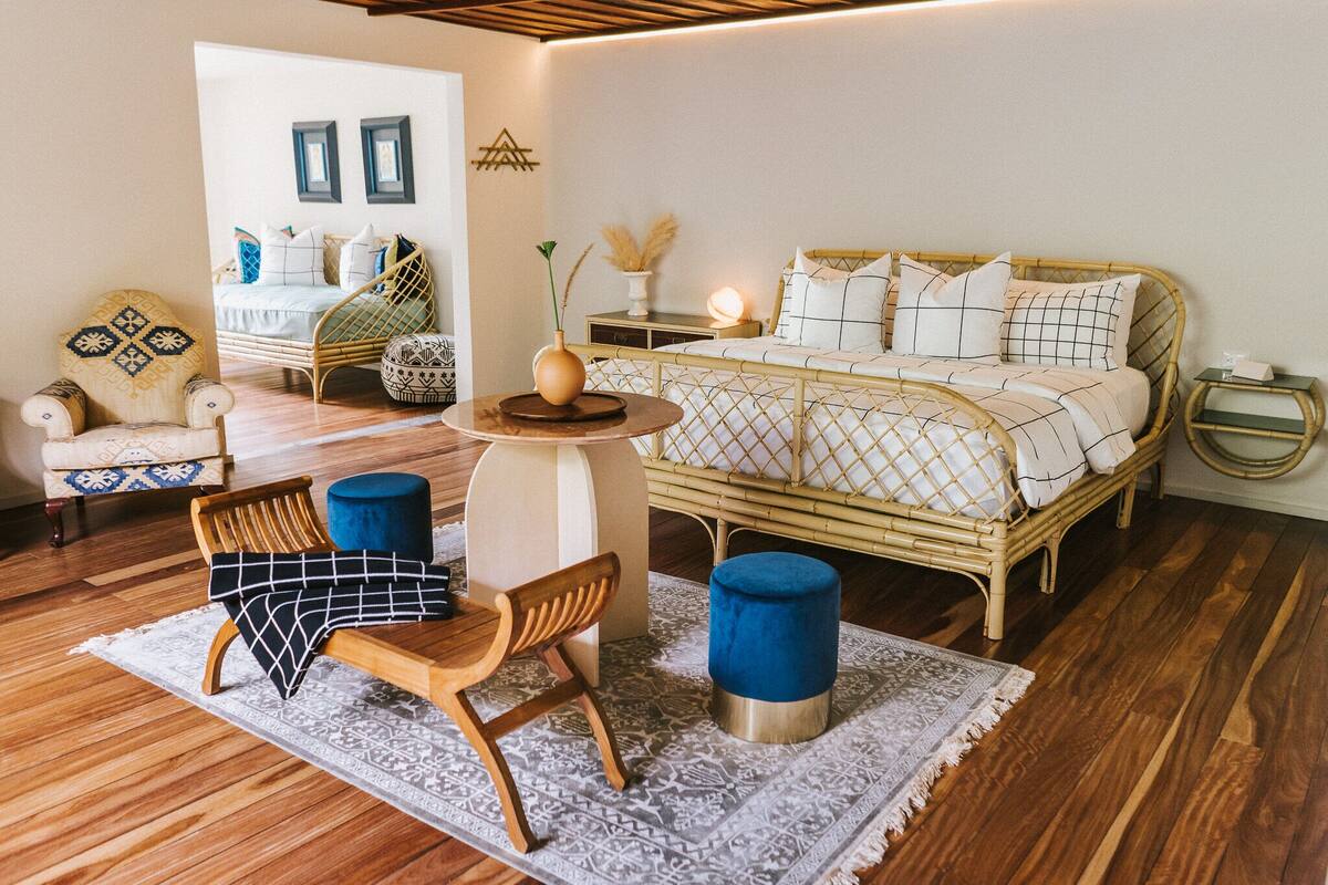 A cozy bedroom with a bed, a chair, a table, and a small side table.
