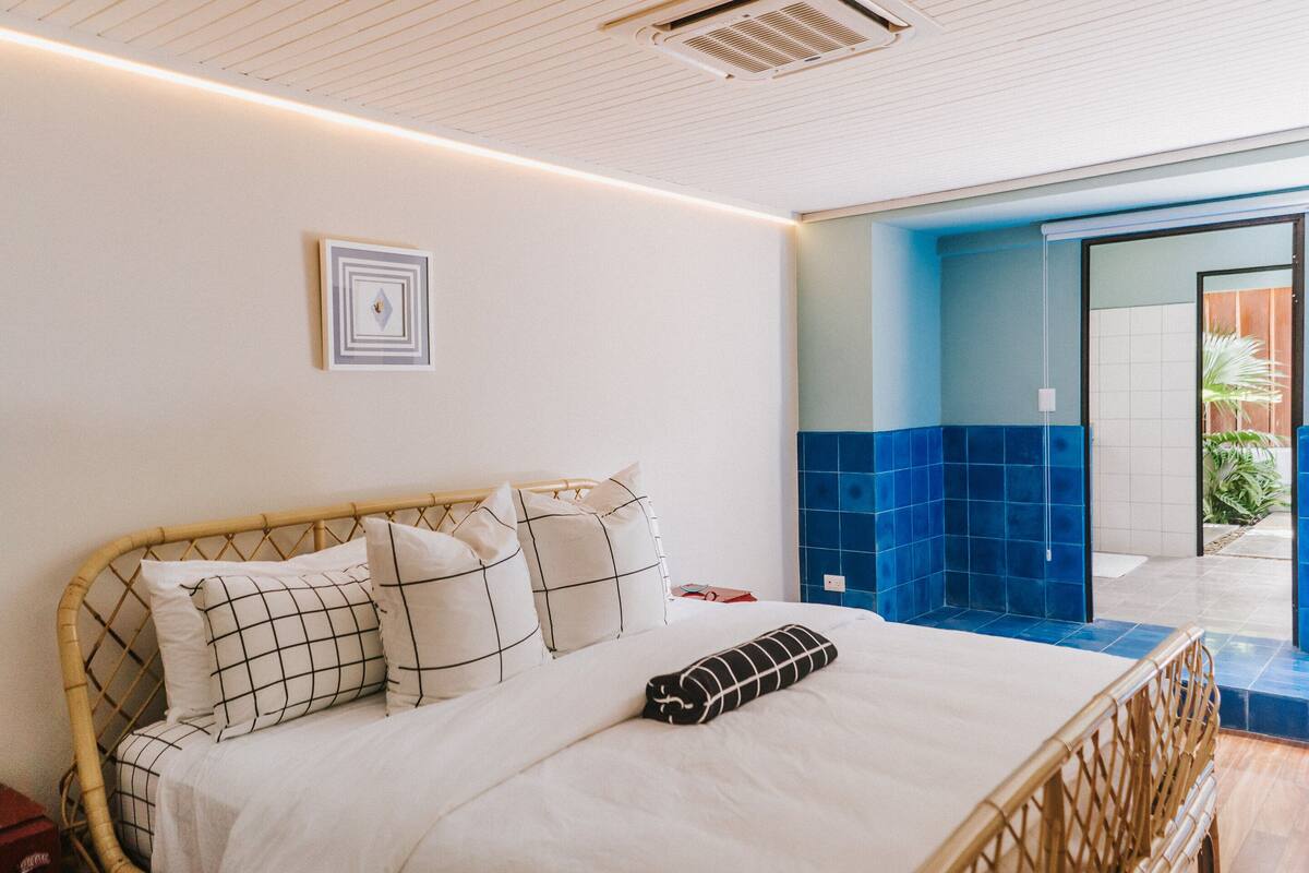 A bedroom with a bed, pillows, and a bedside table.