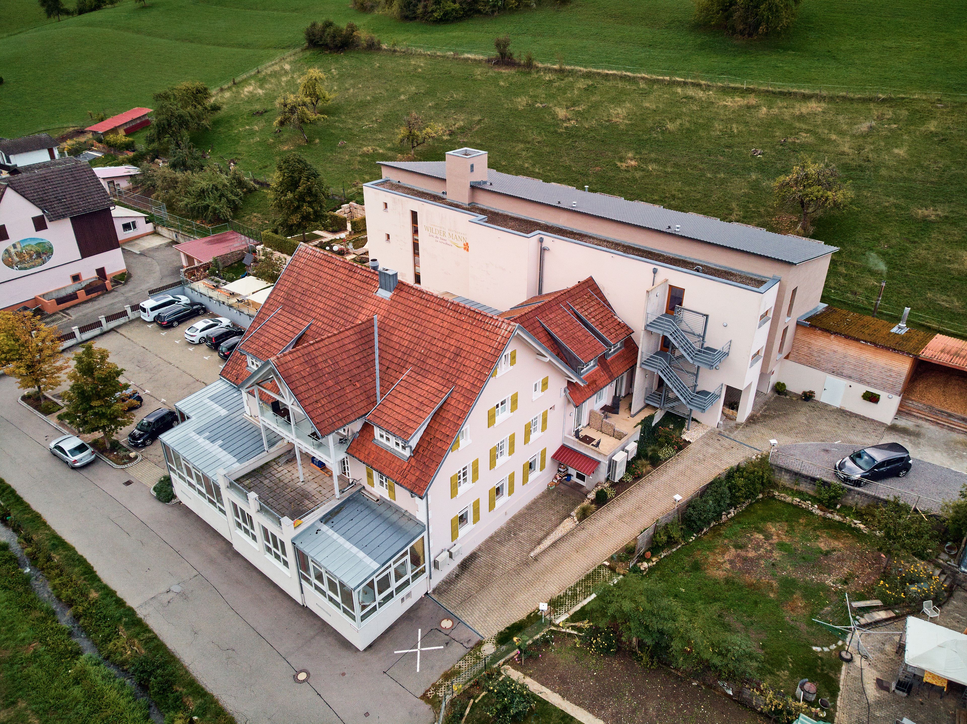 A large building with a red-tiled roof, multiple windows, and a glass extension.