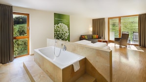 A modern bathroom with a bathtub, a shower, and a sink. There is a balcony with a view of the countryside. - Landhotel Wilder Mann (Eggingen)