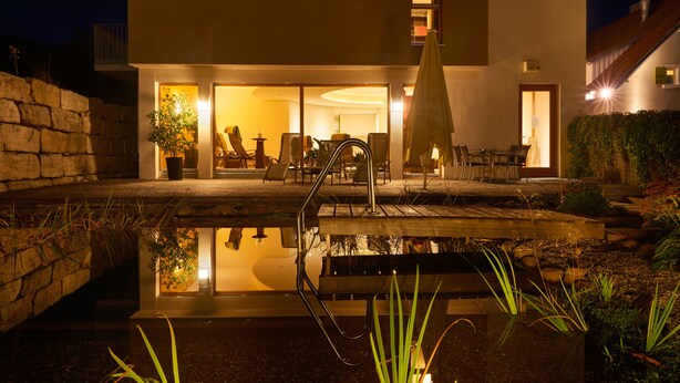 A modern house with a pool, outdoor seating, and a well-lit interior. - Landhotel Wilder Mann (Eggingen)