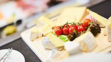 A cheese board with various cheeses and cherry tomatoes.