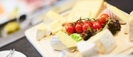 Una tabla de quesos con varios tipos de queso y tomates cherry.