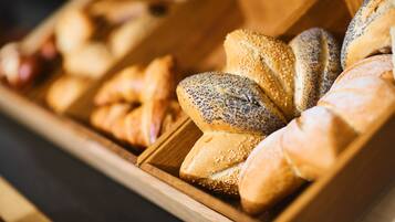 A wooden bread display case with various types of bread, including poppy seed and sesame seed varieties.