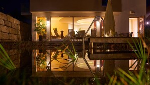 A modern house with a pool, outdoor furniture, and a well-lit interior. - Landhotel Wilder Mann (Eggingen)