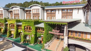 A hotel with a restaurant on the ground floor, featuring a green garden and a staircase leading to the entrance. - Rosengarten Hotel Restaurant (Sopron)