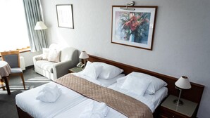 A hotel room with a large bed, two bedside tables, a desk, a chair, and a window with curtains. - Rosengarten Hotel Restaurant (Sopron)