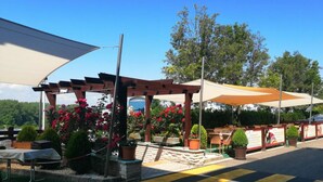 An outdoor seating area with tables and chairs, surrounded by potted plants and flowers. - Rosengarten Hotel Restaurant (Sopron)