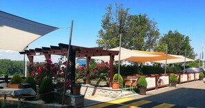 An outdoor seating area with tables and chairs, surrounded by potted plants and flowers. - Rosengarten Hotel Restaurant (Sopron)