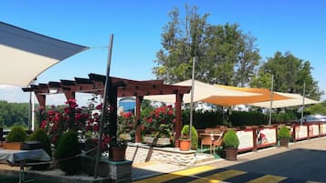 An outdoor seating area with tables and chairs, surrounded by potted plants and flowers.