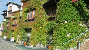A row of buildings with extensive ivy coverage, a visible restaurant sign, and a street in front. - Rosengarten Hotel Restaurant (Sopron)