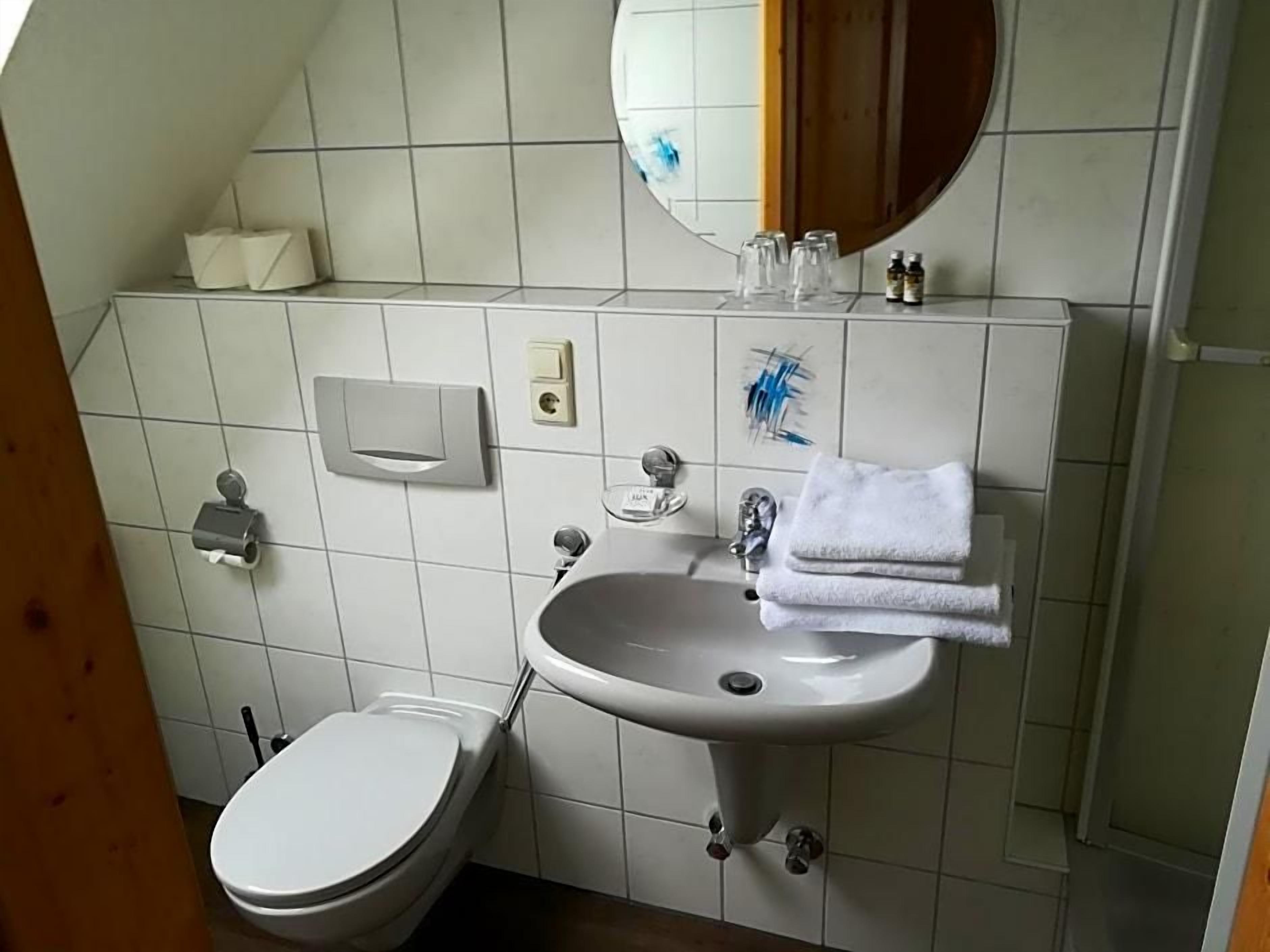 A bathroom with a white sink, a toilet, a mirror, and a towel rack.