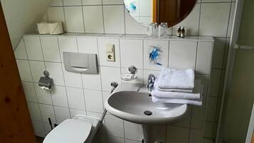 A bathroom with a white sink, a toilet, a mirror, and a towel rack.