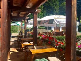 Ein Außenbereich mit Holztischen und -stühlen, umgeben von Blumenbeeten und Sonnenschirmen.