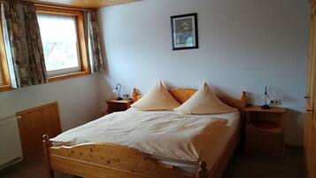 A bedroom with a wooden bed, two bedside tables, a window with curtains, and a framed picture on the wall.