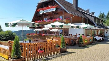Ein Sitzbereich im Freien mit Holztischen und -stühlen, umgeben von einem Holzzaun, und ein Gebäude mit dem Schild 'Gasthof Salenhof'.