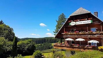 Ein Holzhaus mit einem Schild, auf dem 'Gasthof Salenhof' steht, und Balkonen mit Blumen.