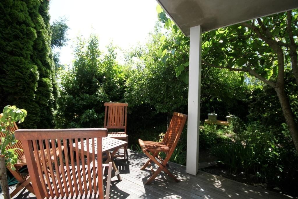 Une terrasse en bois avec une table et des chaises, entourée d’une végétation luxuriante.