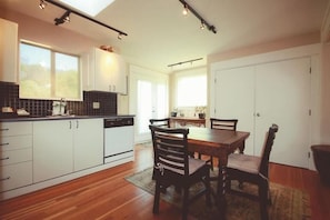 Una cocina moderna con armarios blancos, una mesa de comedor de madera y un ventanal grande.